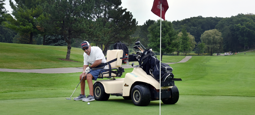 man putting at Lyon Oaks golf course with adaptive golf cart