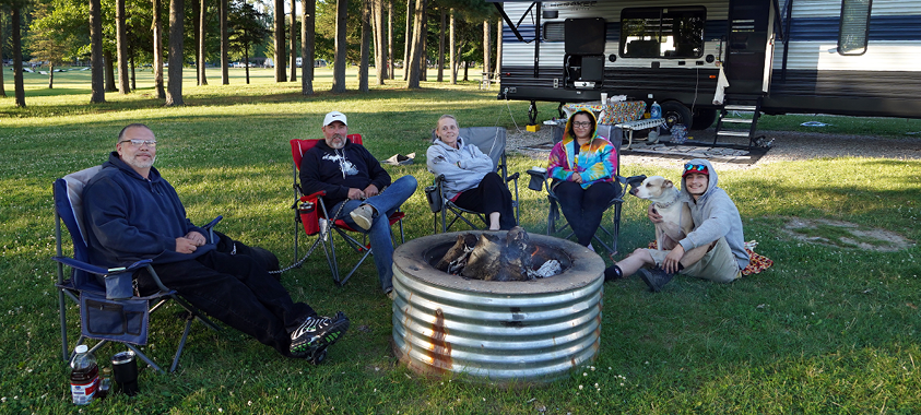 a family sits around the campfire at Addison Oaks campground