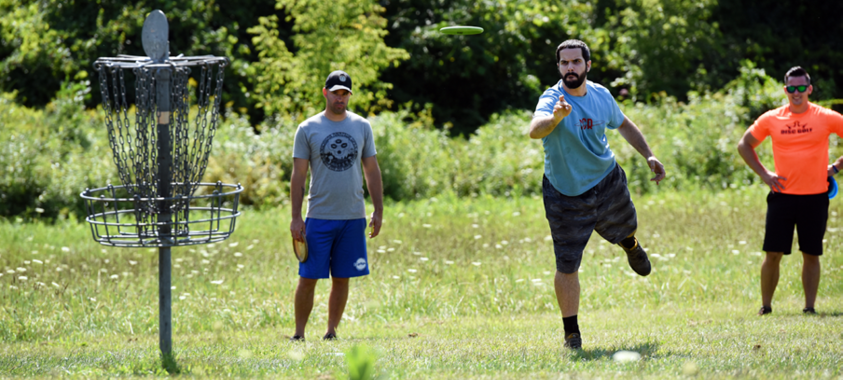 a group of men play disc golf at Addison Oaks park